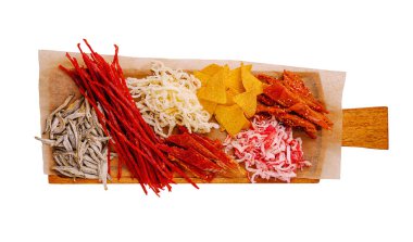 Ahşap bir tahtada günün herhangi bir saatinde toplanma sırasında paylaşmak için mükemmel kurutulmuş balık, doğranmış et ve çıtır cips de dahil olmak üzere bir dizi renkli geleneksel abur cubur yer alır..