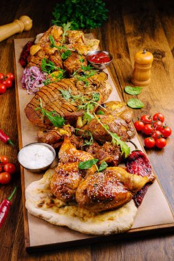 Canlı bir tabakta, çeşitli soslar, taze sebzeler ve ekmekle süslenmiş ızgara tavuk parçaları bir araya getirilmek için mükemmel şekilde servis ediliyor..