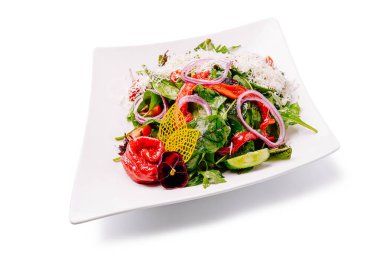 Canlı bir salatada taze yeşiller, kiraz domatesleri, dilimlenmiş salatalıklar ve rendelenmiş peynir ve renkli otlarla kaplı kırmızı soğanlar yer alır. Bu yemek sağlıklı bir yemek için mükemmel..