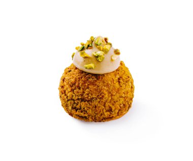 Bu tatlı çıtır çıtır katmanlarla kaplı ve üzeri kremalı ve ezilmiş şam fıstığı ile kaplı yuvarlak bir hamur işi içeriyor. Temiz beyaz bir arkaplanda sunuluyor, dokusunu vurguluyor..