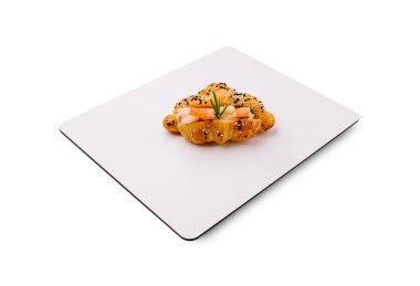 Lezzetli bir hamur işi, deniz mahsulleriyle kaplı saf beyaz bir tabakta oturur ve otlarla süslenir. Mutfak sanatının tazeliğini ve yaratıcılığını ön plana çıkarır..