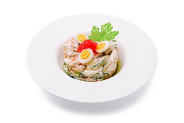 Canlı bir deniz ürünleri salatası beyaz bir kasede güzelce düzenlenir. Dilimlenmiş yumurta ve kırmızı yumurtayla süslenmiş deniz ürünleri katmanları her durum için mükemmeldir..