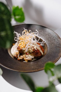 Renkli bir gurme tabağı, çeşitli malzemelerin yer aldığı siyah bir tabakta sanatsal olarak düzenlenir. Yeşilliği çevrelemek taze bir dokunuş ekliyor, yemek deneyimini güçlendiriyor..