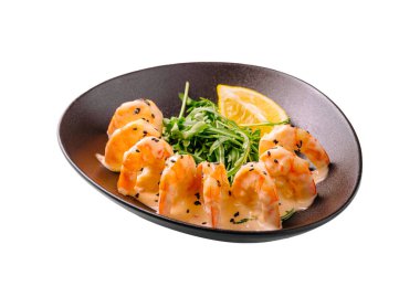 Dolgun karides, taze yeşillikler ve bir dilim limonla tamamlanmış siyah bir tabakta güzelce sıralanmış. Yemek canlı bir sunum için otlarla süslenir..