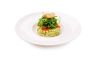 Renkli ve şık bir sebze tartarı beyaz bir tabakta zarif bir şekilde sunulur. Tabakta roka katmanlı doğranmış sebzeler ve taze malzemelerin ön plana çıkarıldığı çıtır çıtır bir malzeme var..