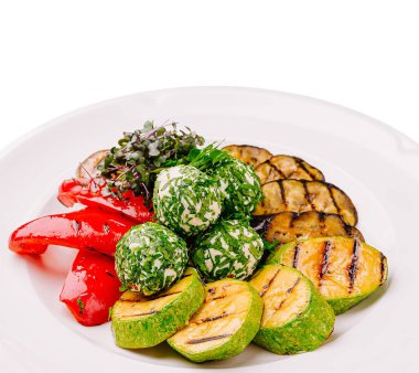 Tabakta ızgara kabak, kırmızı biber ve peynir toplarından oluşan çekici bir düzenleme yer alıyor. Canlı renkler ve taze malzemeler sağlıklı bir yemek için mükemmel, cezbedici bir yemek yaratır..