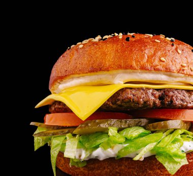 Taze yapılmış bir çizburger, sulu bir biftek köftesi, erimiş peynir, kıtır marul, dilimlenmiş domates, turşu ve kremalı sos, hepsi kızarmış susamlı çöreğin içine yerleştirilmiş..