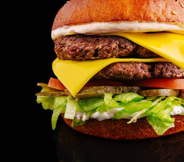 Taze yapılmış çift katlı bir çizburger erimiş peynir, çıtır marul, olgun domates ve kızarmış susamlı çöreğin arasına istiflenmiş turşu sergiler. Tatmin edici bir yemek için her zaman mükemmel..