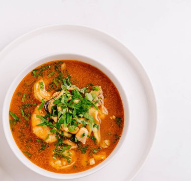 Lezzetli bir tas baharatlı deniz ürünleri çorbası taze otlarla kaplıdır. Canlı kırmızı et suyu karides ve diğer deniz ürünleri içerir. Bu da onu deniz ürünleri aşıkları için davetkar bir yemek yapar..