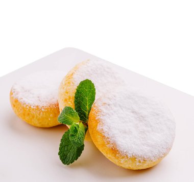 pudra şekerle kaplı süzme peynirli krepler. Parlak beyaz bir tabakta dinleniyorlar. Nane yaprakları tatlıyı süslüyor ve biraz tazelik katıyor. Tatlı bir ikram için mükemmel..