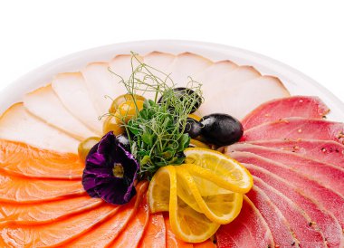 İnce dilimlenmiş somon, biber kabuklu ton balığı ve limon dilimleriyle süslenmiş beyaz et dilimleri, siyah ve yeşil zeytinler, taze yeşiller ve yenilebilir menekşe çiçeğinden oluşan güzel bir servis tabağı. Bu zarif aperatif yemek servisi için idealdir.