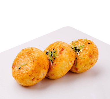 Üç altın sarısı fırında patates köftesi beyaz bir tabakta taze lahanayla süslenir. Dışı kıtır kıtır, içi yumuşak, nefis bir lezzet deneyimi vadediyor..