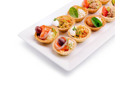 Bir tabakta her biri lezzetli malzemelerle dolu çeşitli gurme tartlar sunuluyor. Deniz ürünleri, sebzeler ve kremalı malzemeler, cazip bir aperatif seçimi sunuyor..