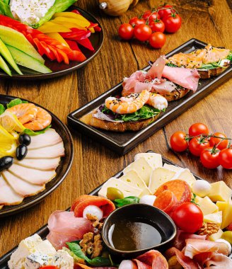 Ahşap masada sergilenen lezzetli mezeler arasında karides, soğuk et, peynir, biber, domates, zeytin ve taze sebzeler yer alıyor. Sosyal toplantı ya da parti için ideal..