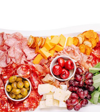 Etler, peynirler, zeytinler ve üzümlerden oluşan canlı bir karışım büyük bir tabakta toplanmak için mükemmel bir şekilde düzenlenmiştir. Paylaşmayı davet eden bu güzel sergi renkleri ve dokular.