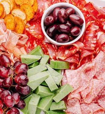 Canlı bir şarküteri panosunda çeşitli pişirilmiş etler, yeşil peynir, zeytin ve üzümler sergileniyor. Kalabalığa şenlik katıyor, kaynaşmak ve paylaşmak için mükemmel..