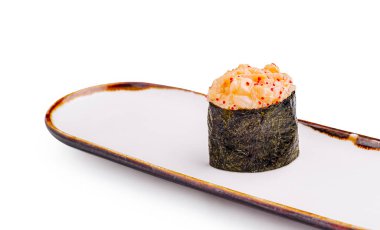 Deniz ürünleri ve sosla dolu tek bir parça suşi, dekoratif kenarlı uzun beyaz bir tabakta sergileniyor ve zarif bir yemek sunumu yaratıyor..