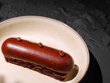 Yuvarlak tabaklar üzerinde sunulan çikolatalı bir tatlı kahve çekirdekleri ile süslenmiş parlak bir tasarım. Zengin, parlak kaplama hamur işi yapma becerisini ön plana çıkarıyor..