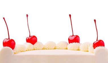 Çok güzel dekore edilmiş bir kutlama pastası krem şanti kıvrımlarının üzerinde üç parlak kırmızı kiraz içerir. Pasta sade beyaz bir arkaplanda duruyor, zarafetini vurguluyor..