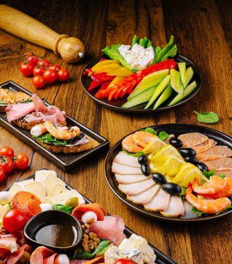 Ahşap masada sergilenen lezzetli mezeler arasında karides, soğuk et, peynir, biber, domates, zeytin ve taze sebzeler yer alıyor. Sosyal toplantı ya da parti için ideal..