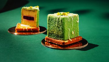 Parlak desenli yeşil katmanlı pastadan yapılmış canlı bir tatlı yansıtıcı bir yüzeyde oturur. Karmaşık detaylar, içinde fındıklı çeşitli renkler bulunan bir dilim içerir..