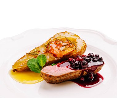 İçinde canlı böğürtlen sosuyla süslenmiş, içinde karamelleştirilmiş armut dilimleri ve bir tutam nane ve gösterişli mutfak sanatının bulunduğu güzel bir tabak ördek göğsü..