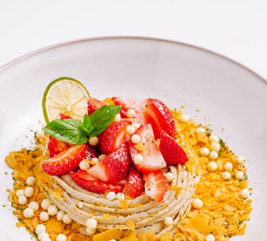 Çok güzel bir şekilde sunulmuş tatlı vitrinleri üzerinde canlı çilekler, limon garnitürleri ve çıtır çıtır parçacıklar olan kremalı bir yuva. Yaz toplantıları ve özel günler için mükemmel..