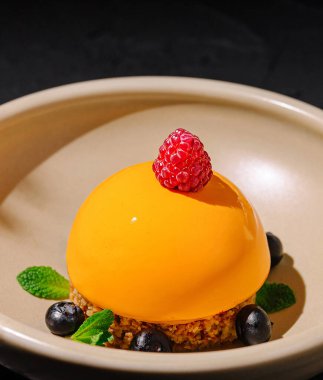 Çıtır çıtır bir tabanın tepesinde parlak turuncu bir kubbe bulunan çok güzel hazırlanmış bir tatlı..