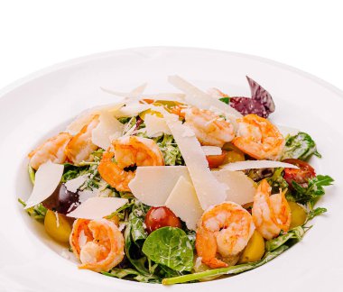 Lezzetli karides, karışık sebze, vişneli domates ve beyaz tabakta sunulan peynir talaşlarından oluşan canlı bir salata. Hafif bir öğle veya akşam yemeği için mükemmel..