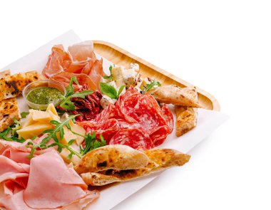 Canlı bir şarküteri tabağında çeşitli et, peynir ve eşlikçiler sergileniyor. Bu görsellik yayılımı bir kutlama ya da gelişigüzel bir toplantı için mükemmel..