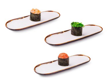 Uzun ve minimalist tabaklar üzerinde üç suşi rulosu düzenli olarak düzenlenir. Her rulo farklı malzemeler içeriyor, çağdaş bir yemek tarzında renk ve dokuların bir karışımını gösteriyor..