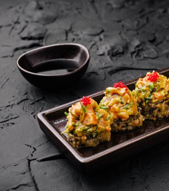 Kıtır kıtır malzemeler ve taze malzemeler içeren dikkatlice düzenlenmiş Japon lezzetleri tabağında lezzet. Tabak, şeffaf ve koyu bir tabakta sosun yanında servis edilir..