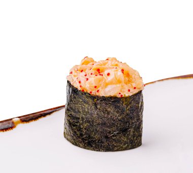 Çok güzel sunulmuş bir suşi parçası, bir deniz yosununun tepesinde bir yığın baharatlı deniz mahsulü barındırıyor, zarif beyaz bir tabakta dinleniyor, aşçılık sanatını ve lezzeti vurguluyor..