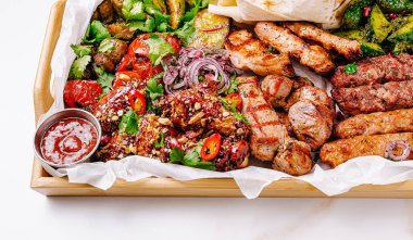 Renkli bir çeşit ızgara et ve sebze ahşap bir tabağı doldurur. Sulu tavuk, baharatlı kebap ve kızarmış sebzeler otlarla süslenir ve yanında keskin bir sosla servis edilir..