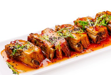 Lezzetli domuz göbeği, canlı bir baharat sosuyla kaplanmış ve susam tohumları ve taze yeşil soğan serpiştirilmiş beyaz bir tepside oturur. Bayramlık bir yemekte paylaşmak için mükemmeldir..