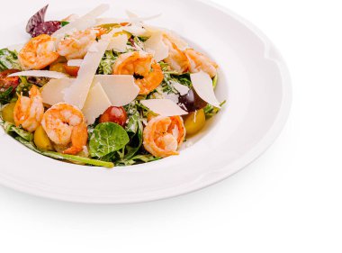 Karides, taze ıspanak, renkli kiraz domatesleri ve parmesan peyniri içeren canlı bir salata, sağlıklı bir öğle yemeği için mükemmel, yuvarlak beyaz bir tabakta güzelce hazırlanmış..