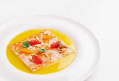 Lezzetli bir tatlı, taze çilek, portakal dilimleri ve bademle kaplı bir kare tatlı üzerine vurgu yapar. Hepsi lezzetli bir sosta servis edilir, her durum için mükemmeldir..