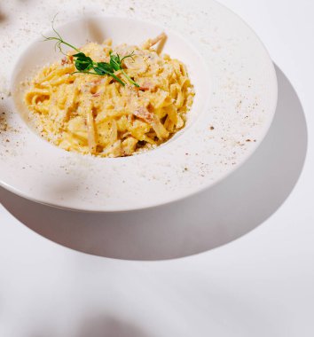 Kremalı bir makarna tabağı, üzerinde otlar ve baharatlar bulunan fettuccine içerir. Tabak zarifçe kaplanmış, zengin sosunu ve davetkar görünümünü sergiliyor..