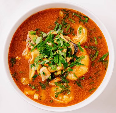 Canlı bir deniz ürünleri çorbası vitrininde karides ve balık bol miktarda taze otlarla kaplı domates suyunda yüzüyor, sıcak bir yemek için mükemmel..