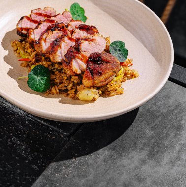 Lezzetli pirinçten bir yatağa yerleştirilmiş taze yeşil yapraklarla süslenmiş zarif bir yemek ortamında gurme pişirme sanatının altını çizen yumuşak tavuk dilimleri..