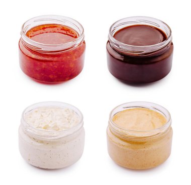 Dört kavanoz farklı sos sergileniyor, biri kırmızı sos, biri koyu sos, biri kremalı beyaz sos, biri de açık renkli sos. Bu lezzetli baharatlar yemekleri geliştirmek için mükemmeldir..