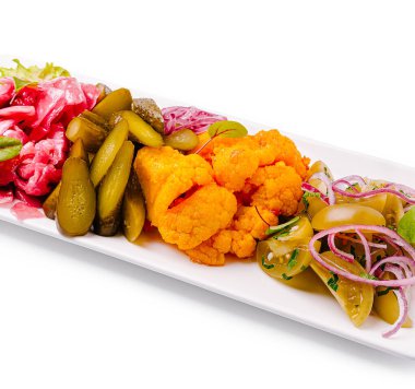 Canlı bir tabakta baharatlı karnabahar, salatalık ve soğan da dahil olmak üzere bir dizi sebze turşusu sergileniyor..