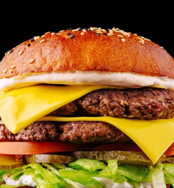 İki köfte, erimiş peynir, taze marul, domates, turşu ve kremalı sostan oluşan leziz bir çift katlı çizburger. Hepsi susamlı bir ekmeğin içine yerleştirilmiş. Lezzetli bir yemek için mükemmel..