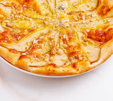 Bu tatlı pizza ince dilimlenmiş armut, kremalı peynir ve ezilmiş fındık ile kaplı altın bir kabuk içeriyor. Her durum için mükemmel ve lezzetli bir lezzet yaratıyor..