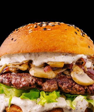 Ağız sulandıran bir hamburger, üzerinde ızgara mantar ve taze marul bulunan sulu bir biftek köftesi sergiler. Susamlı çörek çok hoş bir dokunuş ekliyor. Görsel çekiciliği arttırıyor..