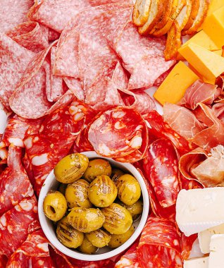 Canlı bir şarküteri tahtası, gün batımında lezzetli bir toplantı için sanatsal peynirler ve marine edilmiş zeytinlerle sunuluyor..