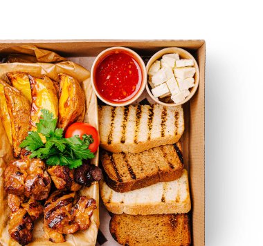 Lezzetli bir tabakta ızgara et şişleri ve yanında taze kişniş ve yanında sosla süslenmiş kızarmış ekmek bulunuyor..