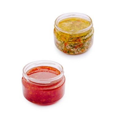 Canlı soslarla dolu iki kavanoz temiz bir yüzeye oturmuş, bir baharatlı kırmızı sos ve bir de keskin yeşil sos sergiliyorlar. Bu ev yapımı kreasyonlar yemekleri geliştirmek için mükemmeldir..