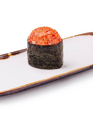 Tek bir parça suşi, parlak beyaz bir tabakta sunuluyor. Suşi, canlı kırmızı tonbalığı soslu deniz yosununa sarılı bir pirinç yatağını, aşçılık sanatını ve tazeliği ön plana çıkarıyor..