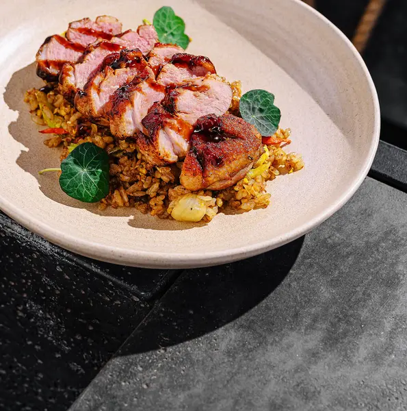 Lezzetli pirinçten bir yatağa yerleştirilmiş taze yeşil yapraklarla süslenmiş zarif bir yemek ortamında gurme pişirme sanatının altını çizen yumuşak tavuk dilimleri..